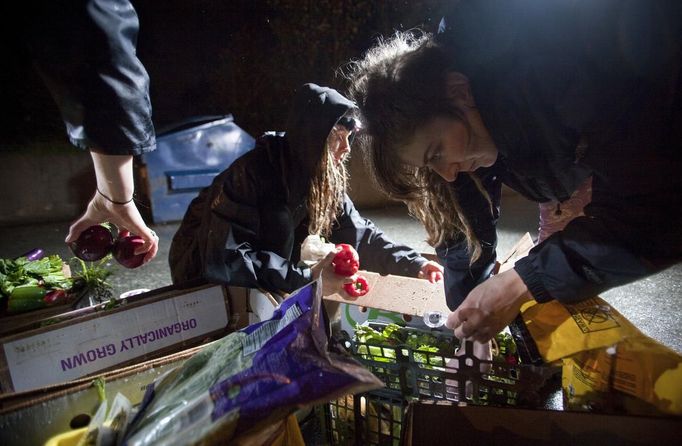 May Wollf (C) and Robin Pickell (R), practising 'freegans', sort through food they plucked out of a dumpster behind an organic grocery store in Coquitlam, British Columbia April 26, 2012. A 'freegan' is someone who gathers edible food from the garbage bins of grocery stores or food stands that would otherwise have been thrown away. Freegans aim to spend little or no money purchasing food and other goods, not through financial need but to try to address issues of over-consumption and excess. Picture taken April 26, 2012. REUTERS/Ben Nelms (CANADA - Tags: SOCIETY) ATTENTION EDITORS PICTURE 13 OF 21 FOR PACKAGE 'DUMPSTER DIVING FOR FOOD' Published: Kvě. 15, 2012, 11:59 dop.