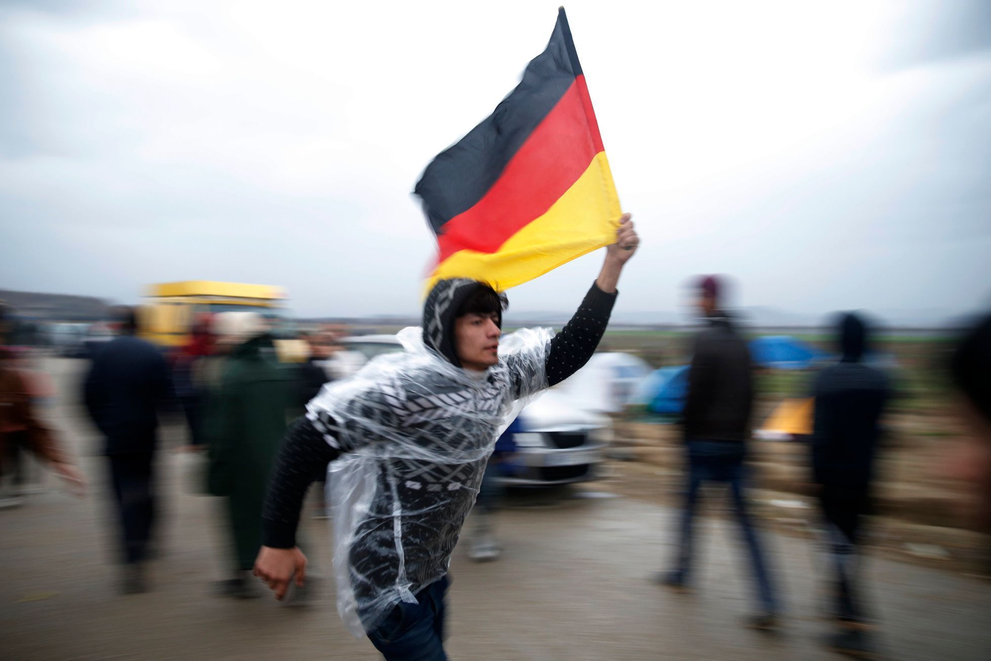 Uprchlík mává německou vlajkou na řecko-makedonském hraničním přechodu Indomeni.