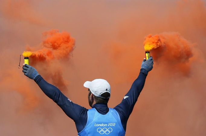 Britský jachtař Ben Ainslie oslavuje se zapálenými dýmovnici své olympijské vítězství (čtvrté za sebou) v kategorii Finn.