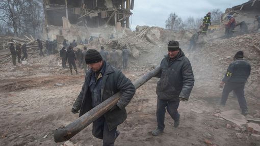 Lidé odstraňují trosky na místě budovy vojenské základny, která byla podle ukrajinských pozemních sil zničena leteckým útokem v oblasti Sumy.