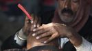 A barber shaves the head of a Hindu devotee on the banks of the river Ganges ahead of the "Kumbh Mela", or Pitcher Festival, in the northern Indian city of Allahabad January 10, 2013. During the festival, hundreds of thousands of Hindus take part in a religious gathering at the banks of the river Ganges. The festival is held every 12 years in different Indian cities. REUTERS/Ahmad Masood (INDIA - Tags: SOCIETY RELIGION) Published: Led. 10, 2013, 8:29 dop.