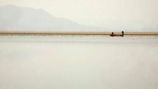 Rybáře rozhazují sítě z loděk u vesnice Š'-c'-kang, která leží u vodního díla Tan-ťiang-kchou v provincii Henan.
