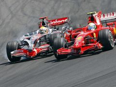 Felipe Massa s Ferrari (vpravo) předjíždí v úvodu Velké ceny Maďarska vítěze kvalifikace Lewise Hamiltona.