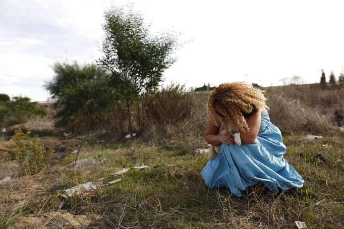 An Israeli women holds her dog as a siren sounds warning of incoming rockets in the southern city of Ashkelon November 16, 2012. The latest upsurge in a long-running conflict was triggered on Wednesday when Israel killed Hamas's military mastermind, Ahmed Al-Jaabari, in a precision air strike on his car. Israel then began shelling the coastal enclave from land, air and sea. REUTERS/Amir Cohen (ISRAEL - Tags: POLITICS CIVIL UNREST ANIMALS) Published: Lis. 16, 2012, 1:17 odp.