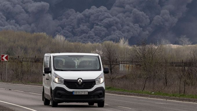 Automobil ujíždí z Lysyčanku, v pozadí dým ze zasažené ropné rafinerie.