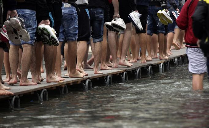 Tourists walk on raised platforms for flood waters in St. Mark Square during a period of seasonal high water in Venice October 27, 2012. The water level in the canal city rose to 127 cm (50 inches) above the normal level, according to the monitoring institute. REUTERS/Manuel Silvestri (ITALY - Tags: ENVIRONMENT SOCIETY TRAVEL) Published: Říj. 27, 2012, 12:35 odp.