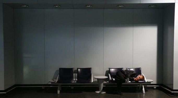 A passenger sleeps at the terminal of German air carrier Lufthansa at the Fraport airport in Frankfurt, September 7, 2012. German air carrier Lufthansa passengers face widespread flight disruption after cabin crew representatives said they continue a series of strikes over pay and cost-cutting measures at Germany's largest airline. The UFO union, which represents around two-thirds of Lufthansa's 19,000 cabin crew called on its members to strike for 24 hours on all German airports on Friday. REUTERS/Kai Pfaffenbach (GERMANY - Tags: BUSINESS EMPLOYMENT CIVIL UNREST TRANSPORT) Published: Zář. 7, 2012, 6:18 dop.