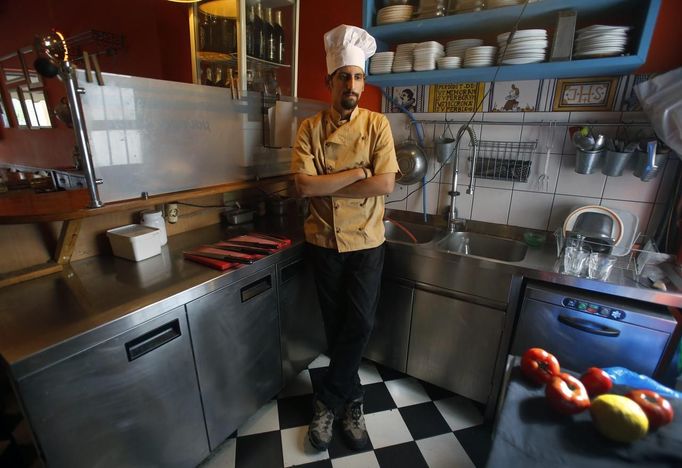 Manolis Ouranos, a 30 year-old cook, poses for a picture in the Mavros Gatos (Black Cat) tavern in Psiri neighboorhood in central Athens May 23, 2012. Manolis studied at Athens Technology University (TEI) for four years where he received a degree in civil engineering. He hoped to find a permanent job in public sector infrastructure but has been working as a cook for four months instead. He now takes cooking lessons which he funds with his salary as a cook.