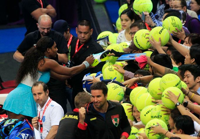 Serena Williams (L) of the Singapore Slammers signs autographs after winning their women's single match against Kirsten Flipkens of the Manila Mavericks during their wome