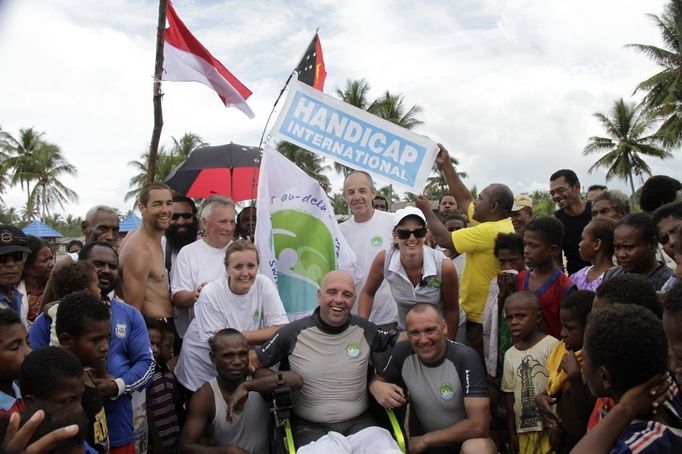 French swimmer Philippe Croizon (C in wheelchair) is joined by crew and Papuan residents after his arrival at the coastal village of Pasar Skow located in Indonesia's eastern province of Papua on May 17, 2012. Croizon, 43, who lost his limbs in an accident braved strong winds and currents to swim from Papua New Guinea to Indonesia on May 17, in the first stretch of a mission to swim between five continents. Croizon, who uses prosthetic limbs with flippers attached took seven and a half hours for the 20 kilometre (12-mile) journey.