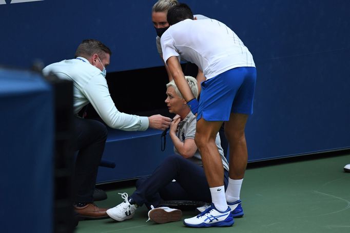 Sep 6, 2020; Flushing Meadows, New York, USA; Novak Djokovic of Serbia and a tournament official tend to a linesperson who was struck with a ball by Djokovic against Pabl