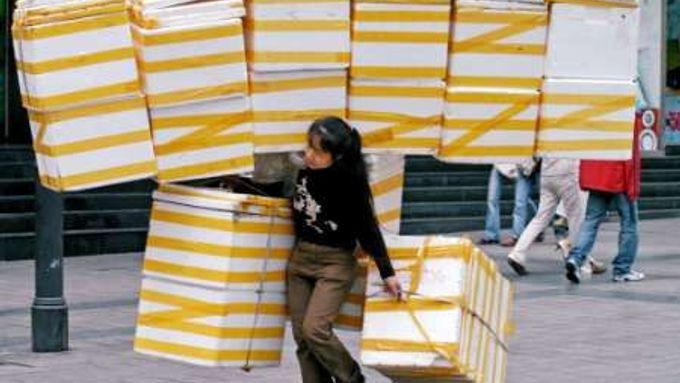 Náklad krabic se snaží pobrat žena na ulici čínského města Chongqing.