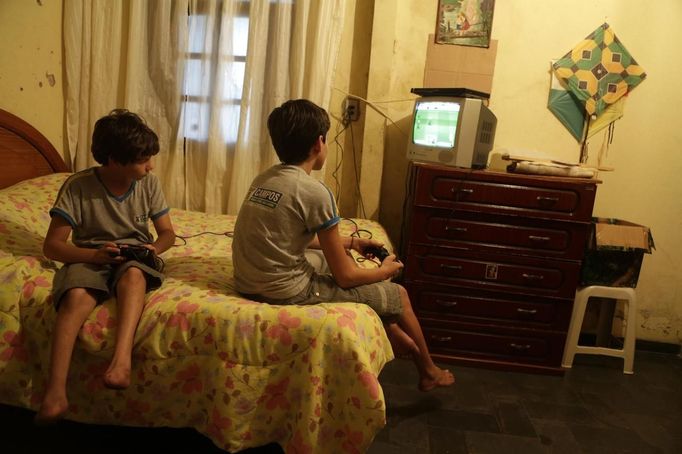 Gabriel Muniz (L), 11, plays a video game with his brother Mateus at home in Campos dos Goytacazes, 274 kilometres (170 miles) northeast of Rio de Janeiro August 22, 2012. Despite being born with malformation of his feet, fourth grader Gabriel puts in hours into soccer everyday in his neighbourhood. He aspires to be a professional soccer player just like his idol Argentina's Lionel Messi of Barcelona FC. Picture taken on August 22. REUTERS/Ricardo Moraes (BRAZIL - Tags: SPORT SOCCER SOCIETY HEALTH) Published: Srp. 24, 2012, 2:25 dop.