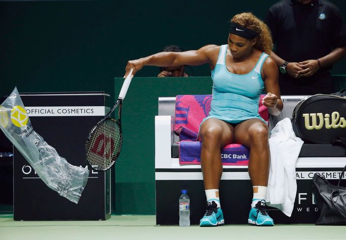 Serena Williams of the U.S. takes the plastic cover off a new racquet after smashing her first one during her WTA Finals singles semi-finals tennis match against Caroline