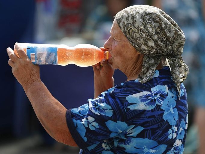 A woman drinks soda in central Donetsk June 25, 2012. Temperatures recently reached up to 35 degrees Celsius (95 degrees Fahrenheit) in eastern Ukraine. REUTERS/Yves Herman (UKRAINE - Tags: SOCIETY ENVIRONMENT) Published: Čer. 25, 2012, 2:31 odp.