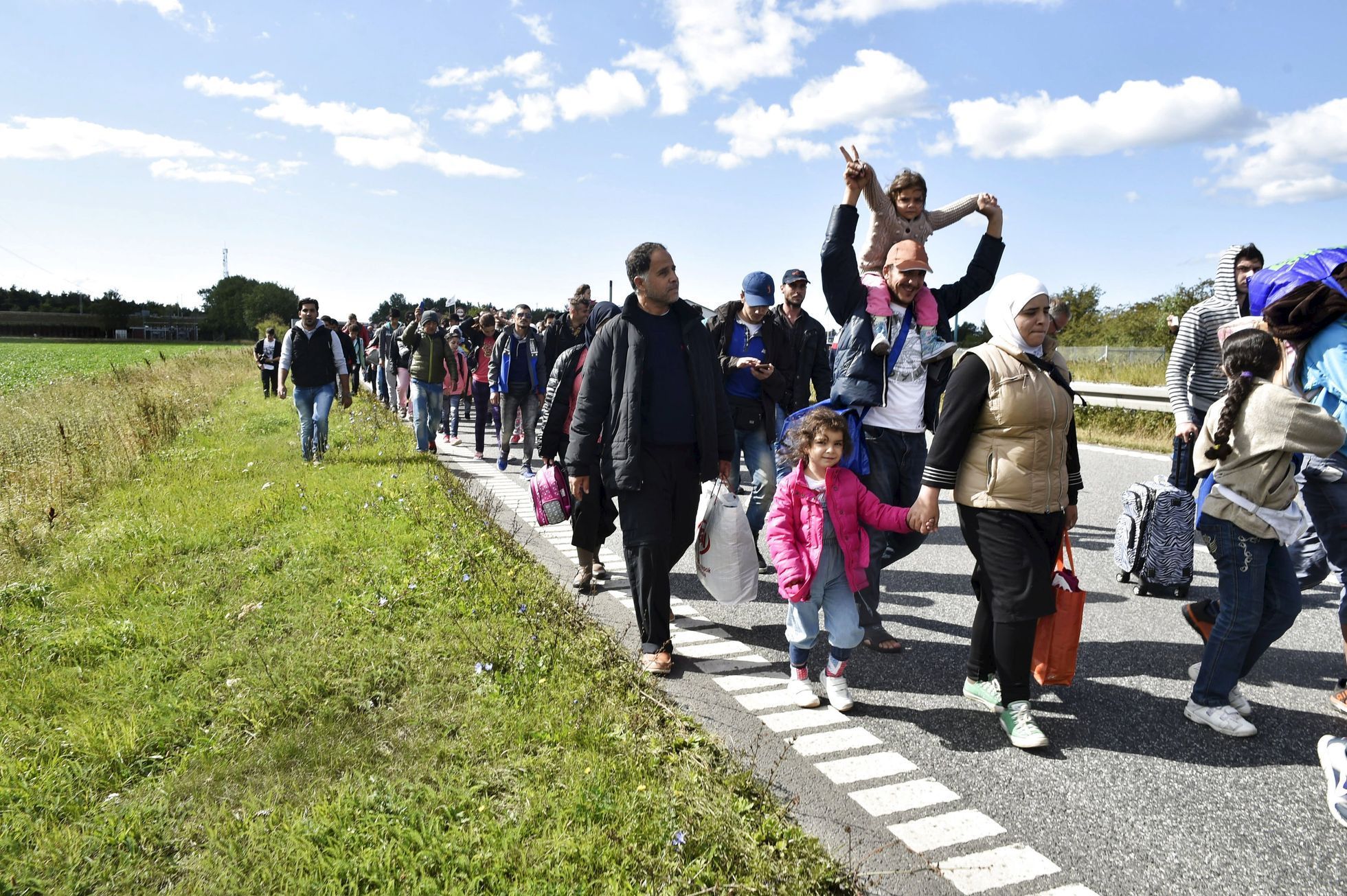 A large group of migrants, mainly from Syria, walk towards the north on a highway in Denmark