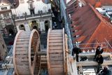 Ke zvedání soch používají restaurátoři historický dřevěný jeřáb, zapůjčený z Pražského hradu. Je postaven na lešení v úrovni ochozu věže, tedy asi třicet metrů nad zemí. Za jeřábem pohled na Staré město.