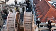 Ke zvedání soch používají restaurátoři historický dřevěný jeřáb, zapůjčený z Pražského hradu. Je postaven na lešení v úrovni ochozu věže, tedy asi třicet metrů nad zemí. Za jeřábem pohled na Staré město.