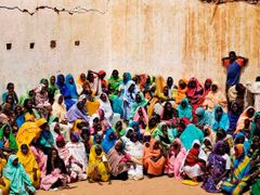 Uprchlice z Dárfúru čekají před budovou, kde se rozdávají potraviny.