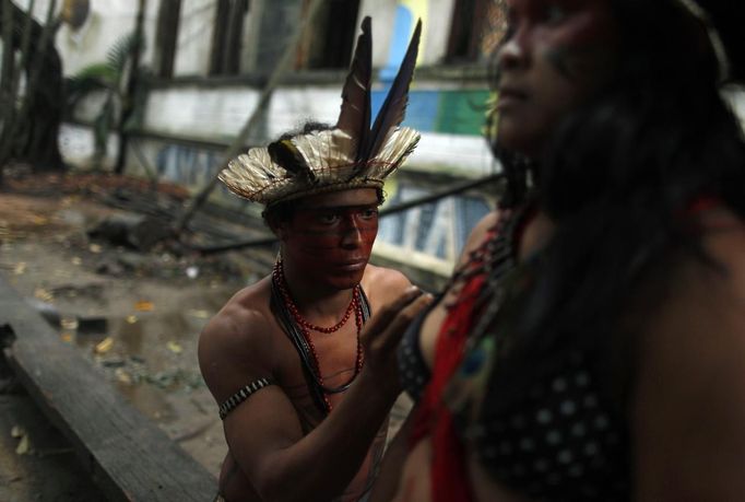 A Brazilian Indian paints on the body of an Indian woman before a ceremony at the Brazilian Indian Museum in Rio de Janeiro, March 18, 2013. A native Indian community of around 30 individuals who have been living in the abandoned Indian Museum since 2006, were summoned to leave the museum in 72 hours by court officials since last Friday, local media reported. The group is fighting against the destruction of the museum, which is next to the Maracana Stadium, to make way for a planned 10,000-car parking lot in preparation for the 2014 Brazil World Cup. REUTERS/Pilar Olivares (BRAZIL - Tags: SOCIETY CIVIL UNREST) Published: Bře. 18, 2013, 10:38 odp.