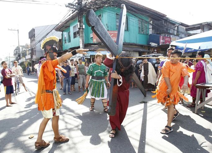 Felix Anaye, 32, portraying Jesus Christ, carries a wooden cross while he is whipped by a man portraying a Roman soldier during a procession ahead of Good Friday in Mandaluyong city, metro Manila March 28, 2013. Penitents will be nailed to a cross on Good Friday in a display of religious devotion in the Philippines, a predominantly Catholic country. Holy Week is celebrated in many Christian traditions during the week before Easter. REUTERS/Romeo Ranoco (PHILIPPINES - Tags: RELIGION SOCIETY) Published: Bře. 28, 2013, 6:04 dop.