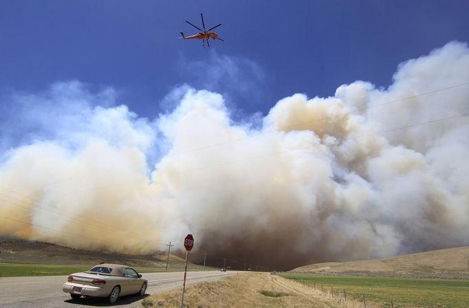 A helicopter flies down US highway 89 as smoke from the Wood Hollow fire fills the sky north of Fairview, Utah, June 26, 2012. More than 500 structures have been threatened by the Wood Hollow fire, forcing up to 1,500 people from homes. REUTERS/George Frey (UNITED STATES - Tags: ENVIRONMENT DISASTER TPX IMAGES OF THE DAY) Published: Čer. 26, 2012, 10:03 odp.