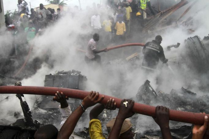 People help rescue workers extinguish a fire after a plane crashed into a neighbourhood in Ishaga district, an outskirt of Nigeria's commercial capital Lagos June 3, 2012. There were no survivors among the 147 people on board a domestic passenger aircraft that crashed in the Nigerian city of Lagos on Sunday, an official of the National Emergency Management Agency (NEMA), told Reuters. REUTERS/Akintunde Akinleye (NIGERIA - Tags: DISASTER TRANSPORT) Published: Čer. 3, 2012, 9:01 odp.