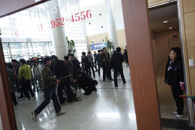 Journalists wait for South Korean employees to return from the Kaesong Industrial Complex (KIC) as a cleaner looks on, at South Korea's CIQ (Customs, Immigration and Quarantine) office, just south of the demilitarised zone separating the two Koreas, in Paju, north of Seoul, April 3, 2013. North Korean authorities were not allowing any South Korean workers into a joint industrial park on Wednesday, South Korea's Unification Ministry and a Reuters witness said, adding to tensions between the two countries. REUTERS/Kim Hong-Ji (SOUTH KOREA - Tags: MILITARY POLITICS BUSINESS MEDIA) Published: Dub. 3, 2013, 6:58 dop.