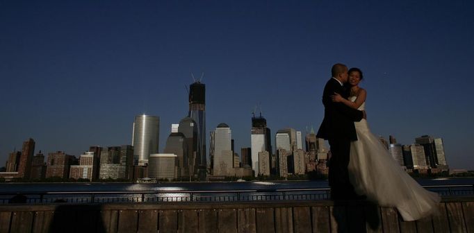 A couple, posing for their pre-wedding photographs, are back-dropped by the One World Trade Center and Manhattan skyline as seen from New Jersey April 29, 2012. A steel column will be hoisted atop the One World Trade Center on Monday, making it New York's tallest building, local media reported. The first column of the 100th floor of One World Trade Center will bring the tower to a height of 1,271 feet (387 meters), making it 21 feet (6 meters) higher than the Empire State Building, media said. REUTERS/Eduardo Munoz (UNITED STATES - Tags: CITYSPACE SOCIETY) Published: Dub. 30, 2012, 5:06 dop.