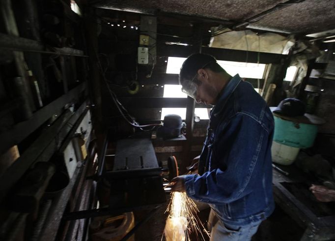 Luis Salgado, nicknamed Chucho, sharpens a knife at his home in the village of Sagua La Grande in central Cuba, March 2, 2013. Chucho was granted a U.S. visa based on his father's status as legal resident in Texas, and he was reunited in Miami with his father, Jesus Salgado, who had escaped Cuba on a frail boat ten years earlier. The Salgados are among many Cubans taking advantage of Cuba's new travel policy in place since last January, which allows citizens to leave the country with just a passport and no need for much-hated exit visas required since 1961. Picture taken March 2, 2013. REUTERS/Desmond Boylan (CUBA - Tags: POLITICS SOCIETY) Published: Dub. 11, 2013, 12:59 odp.